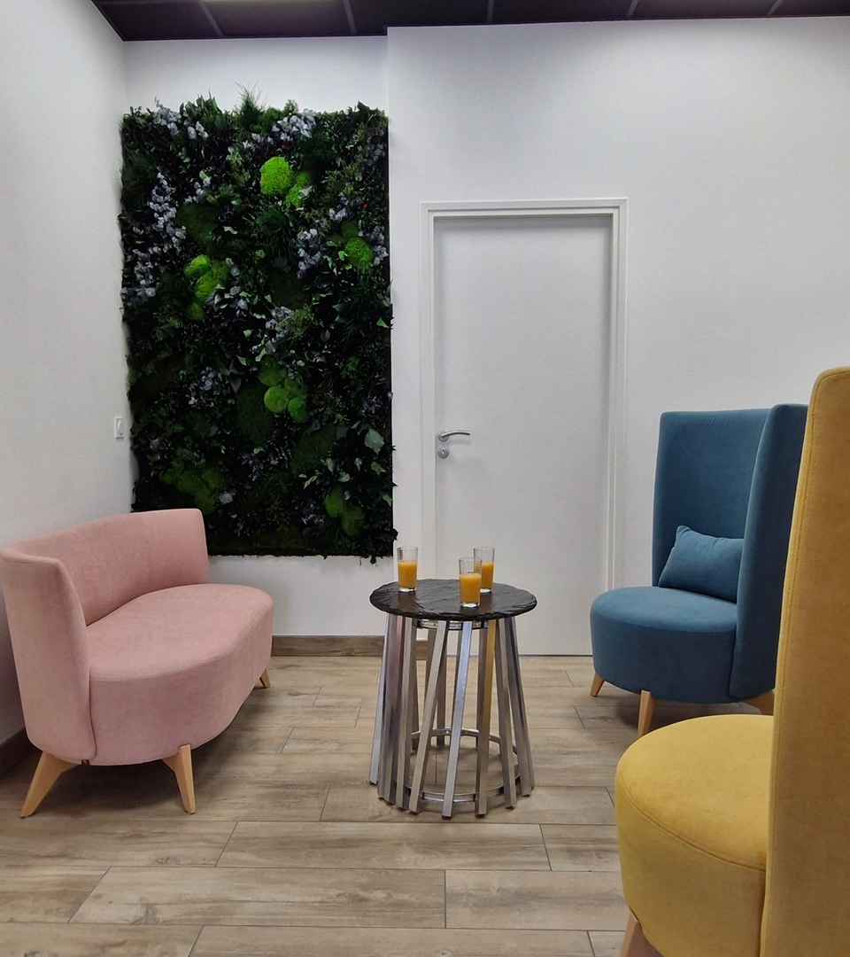 Coin détente du centre Antre2o composé de 3 fauteuils de couleur rose, bleu et moutarde ainsi qu'une petite table sur laquelle se trouve 3 verres de jus d'orange u
